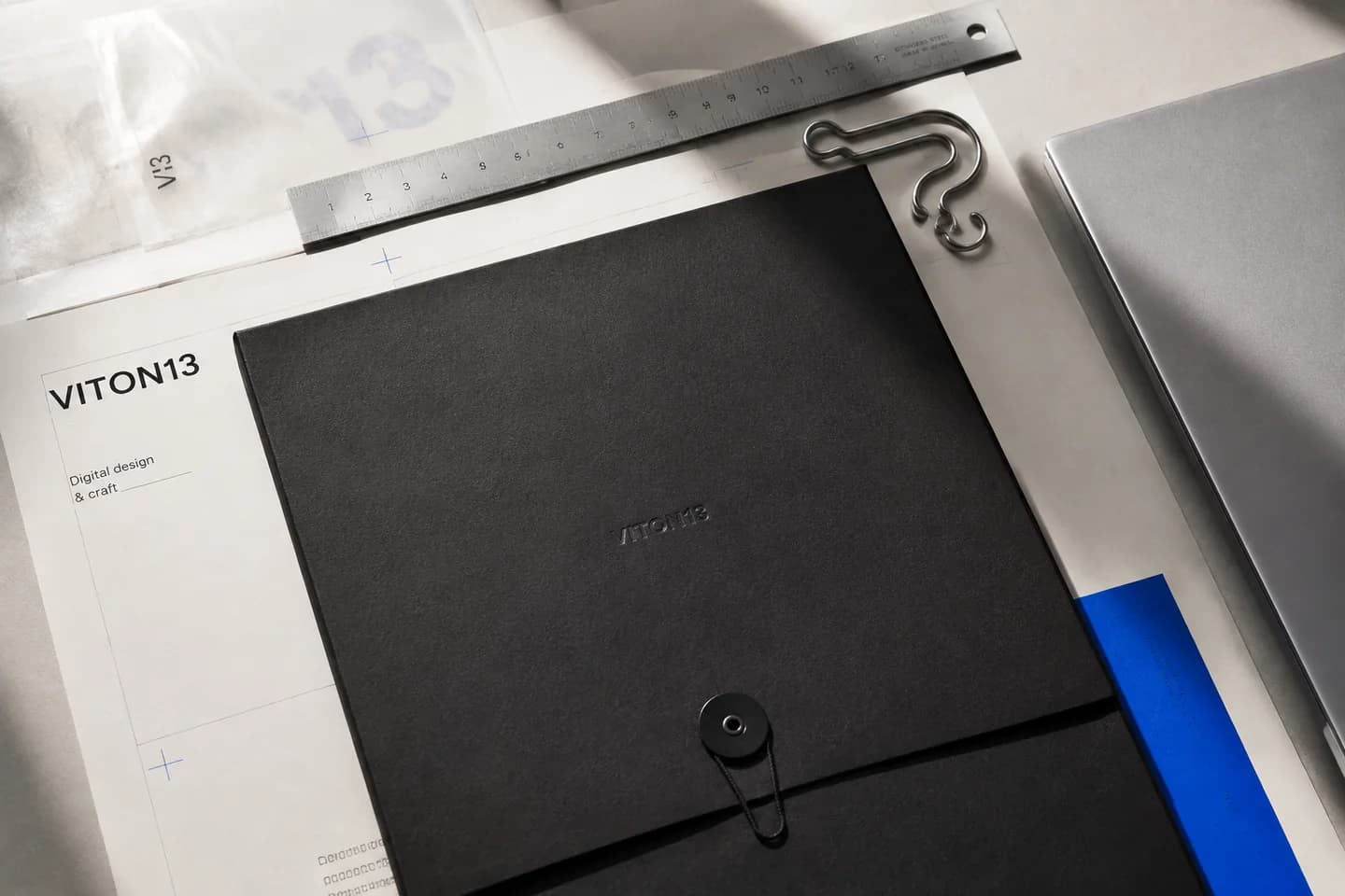 Black document folder, steel ruler and design layouts on a desk