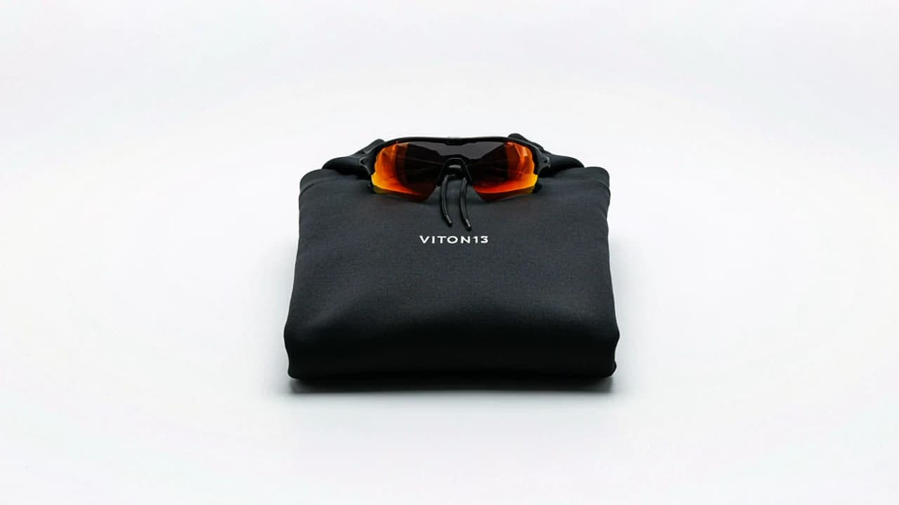 Folded black VITON13 sports hoodie with orange-lens sunglasses on top