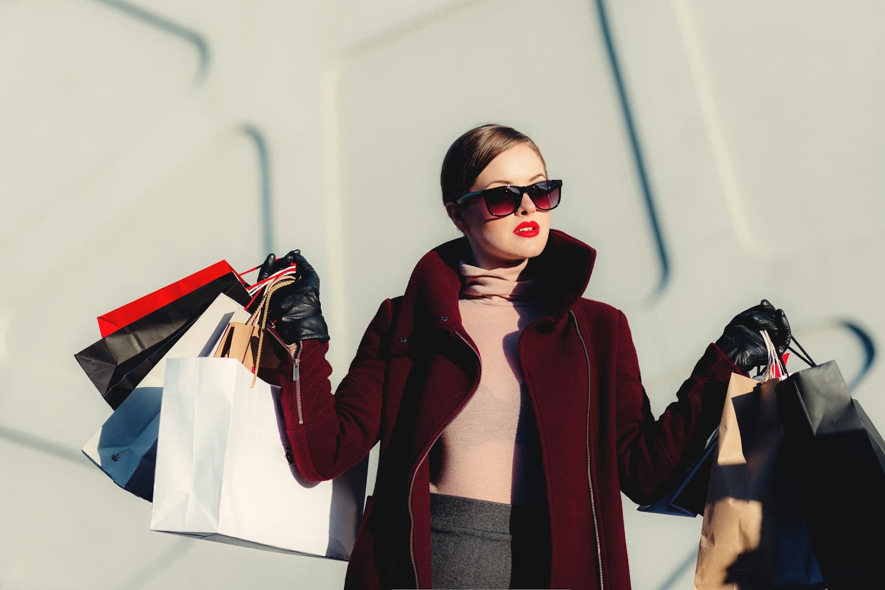 Shoppers carrying bags past a bright storefront