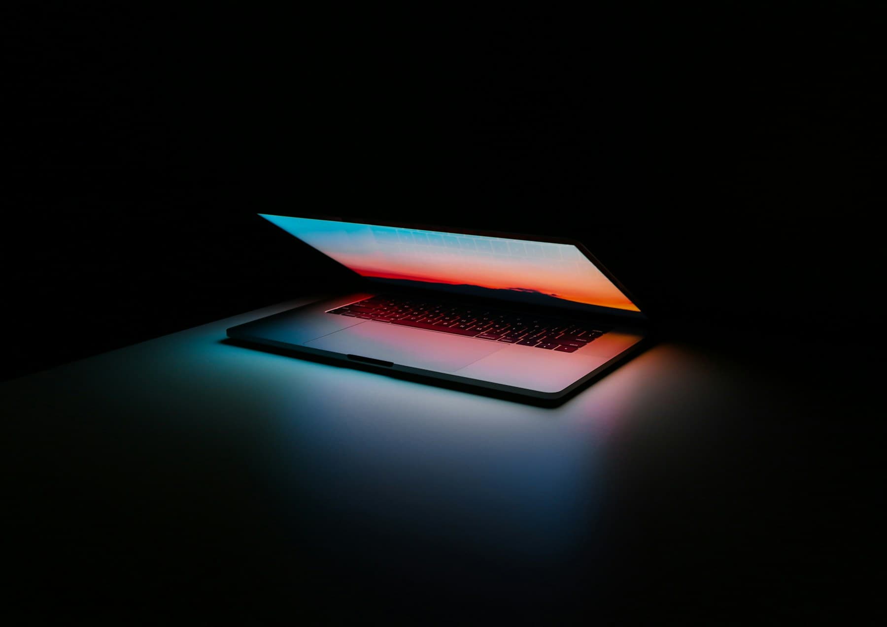 Two open laptops on a dark reflective surface