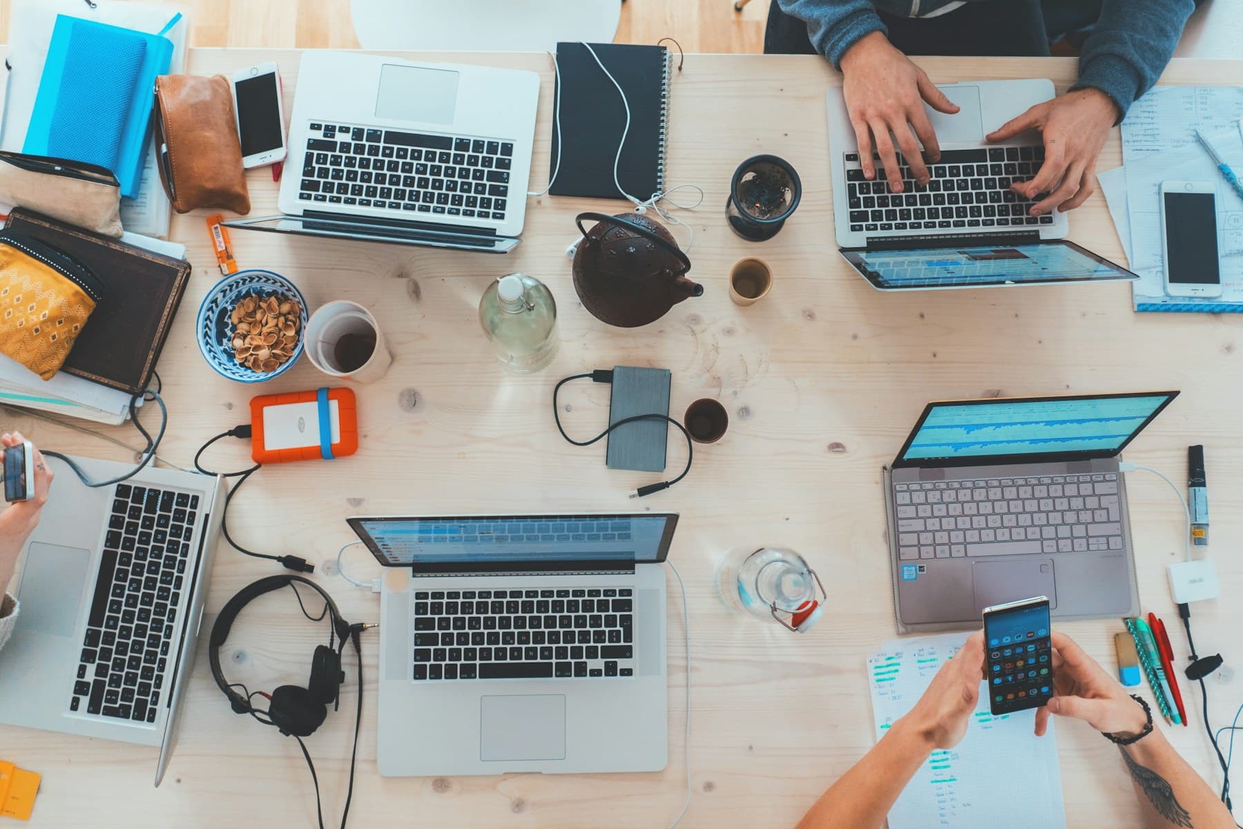 Overhead view of a shared desk covered with devices and notes