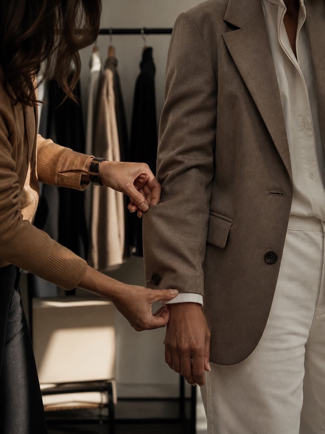 Stylist checking the sleeve length and proportion of a tailored jacket during a fitting